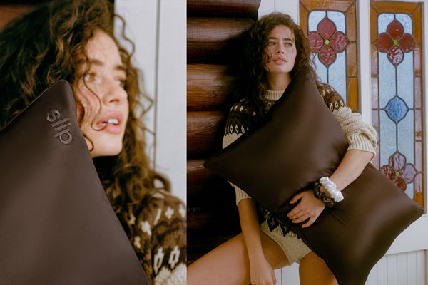 A split-screen lifestyle image showing a model holding a large dark brown silk pillowcase. The left panel is a close-up of the model's face and the pillow, while the right panel shows her sitting against a rustic wooden wall and stained glass window.