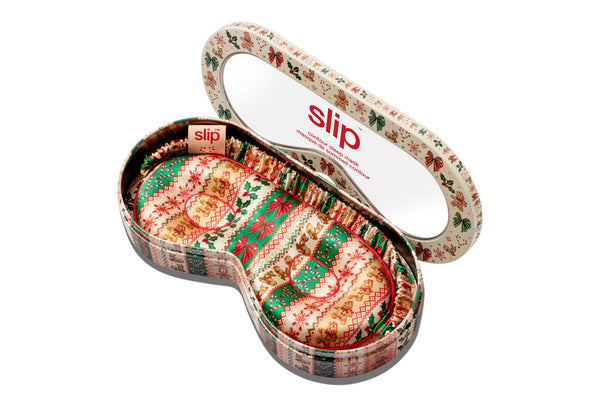 A slip contour sleep mask tin box with a festive Christmas pattern, opened with a sleep mask inside. 