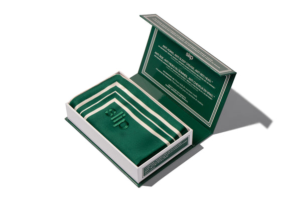 Opened packaging of a green slip silk pillowcase with slip branding on a white background
