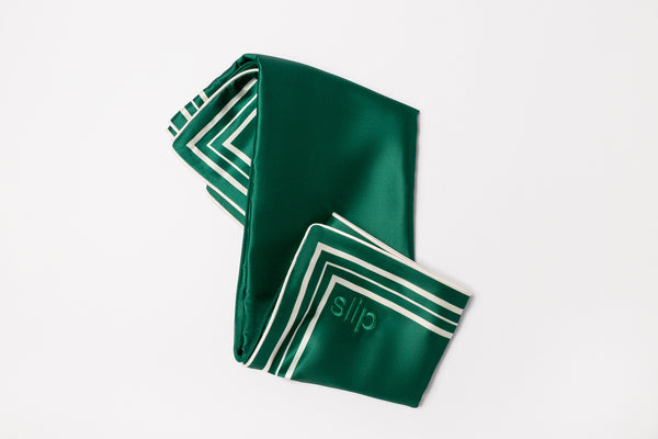 Green silk pillowcase with white stripes and slip embroidery on a light grey background